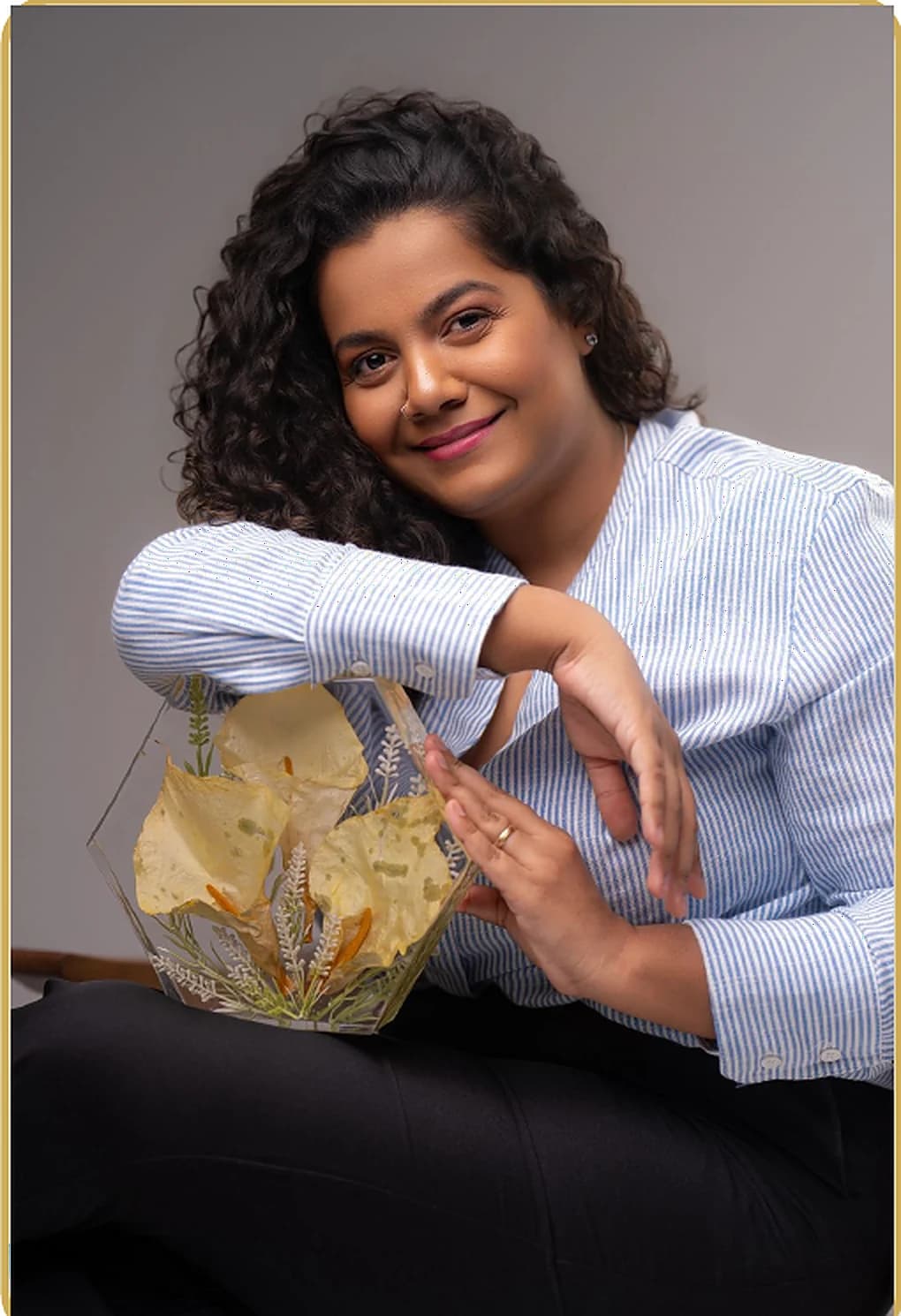 Artesa segurando uma peça de resina com flores eternizadas